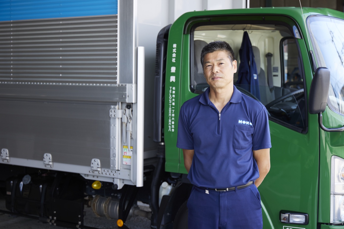 トラックの前に立つHOKOのドライバー（自社スタッフ）